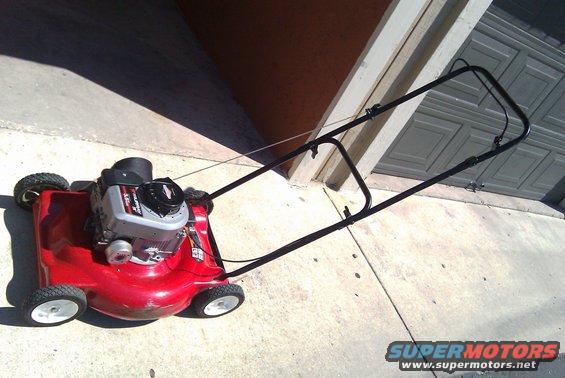 Red push mower with a Briggs & Stratton engine parked on a concrete driveway