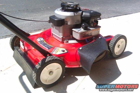 Red lawn mower with a gas engine and black handle. Some text labels are visible on the deck