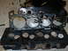 1979 Ford F-150 - Disassembled engine components, including a cylinder head and gasket, are laid out on a floor.