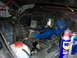 1979 Ford F-150 - The engine bay of a vehicle, blue valve covers and a prominent brake booster, with a can of WD-40 and a beer can visible.