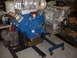 1965 Ford 427 - Two V8 engines with superchargers are displayed on engine stands in a workshop.