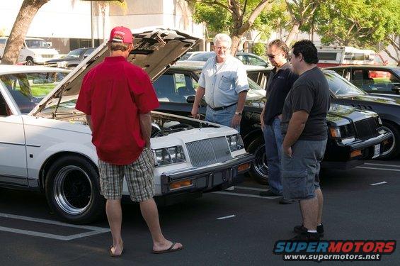 White 1980s Buick Regal front view, hood open, parked at car show
