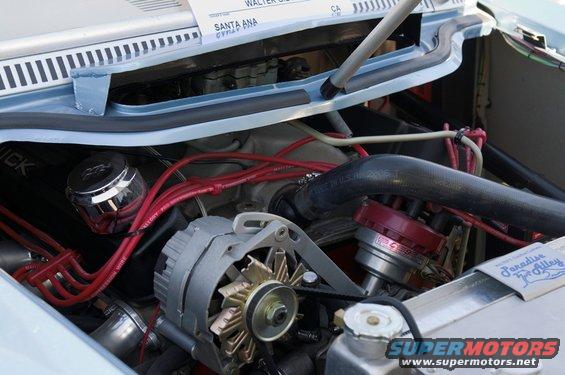 Engine bay with alternator, distributor, and red spark plug wires. Text on a tag reads 'Paradise Alley'
