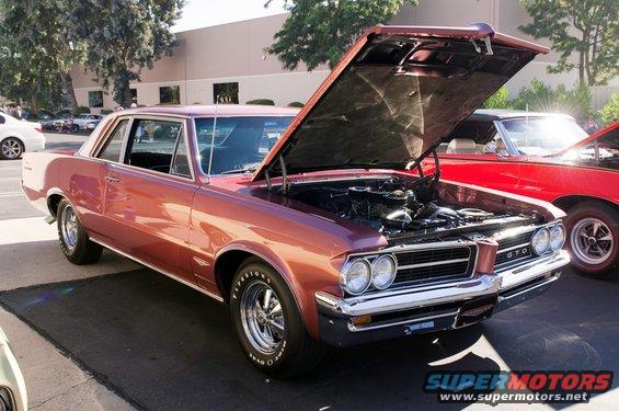 Rose gold 1966 Pontiac GTO coupe with hood open, showing engine. Chrome grille with 'GTO' badge