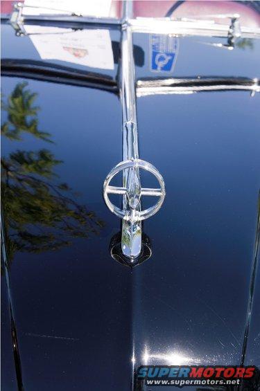 Black car hood ornament with a circular element and a vertical bar