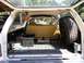 1987 Dodge 1500 - View into the cargo area of an SUV, a spare tire mounted on the side and a folded-down rear seat.
