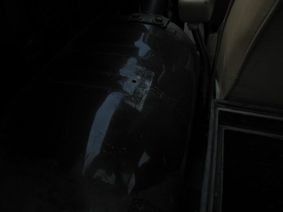 Interior wheel well with visible rust and a small hole