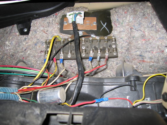 Wiring harness and fuse box with multiple wires connected to terminals. A silver cylindrical component is visible
