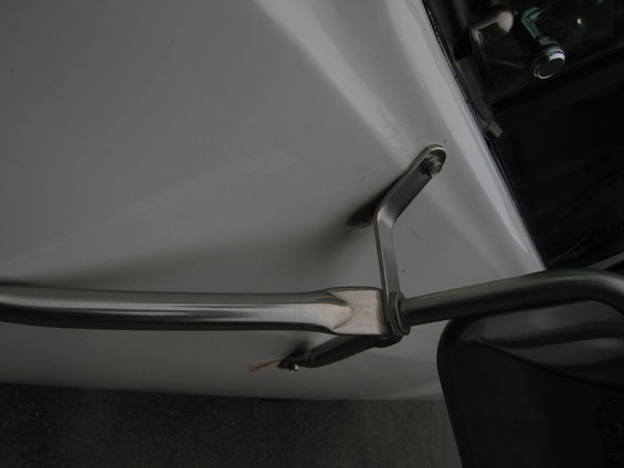 Chrome trim piece attached to a white vehicle body with a metal bracket