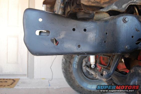 Black painted vehicle frame section with visible suspension components and tire