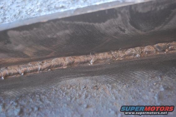 Close-up of a rough, welded metal seam on a dark, textured surface