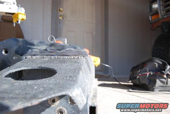 Close-up of welding on a vehicle frame with a tool and bag in the background