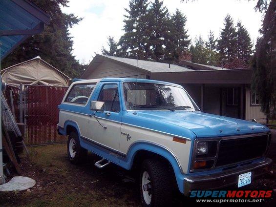 1981 Ford Bronco parked in a driveway with a house and trees in the background
