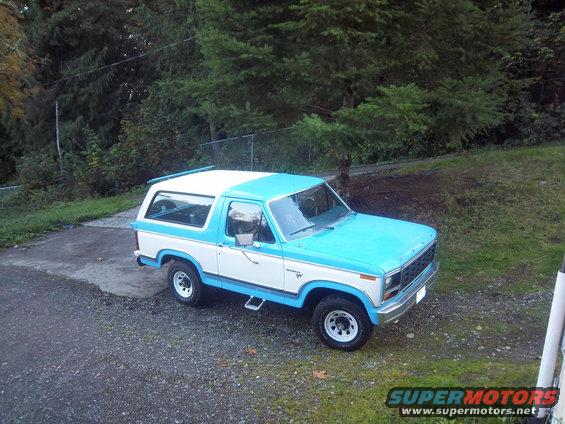 Blue and white Ford Bronco parked on a gravel driveway
