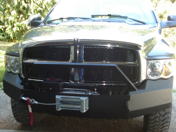 Black aftermarket truck bumper with a winch and red tow strap