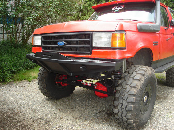Red Ford truck front with aftermarket bumper, snorkel, and ARB sticker
