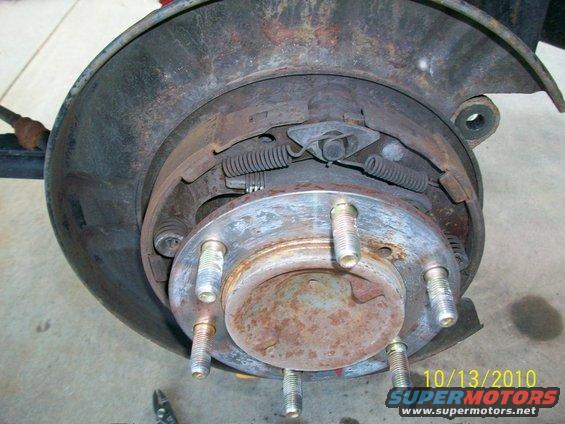 Rusty car brake drum assembly with visible brake shoes and springs