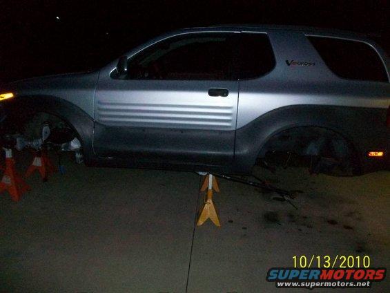 Silver 1999 Isuzu Vehicross with wheels removed, supported by jack stands