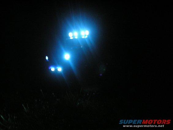 Darkness with bright blue auxiliary lights on a vehicle, grass in foreground