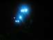 1994 Ford Escort - A vehicle is illuminated by bright blue auxiliary lights in the dark, with grass visible below.