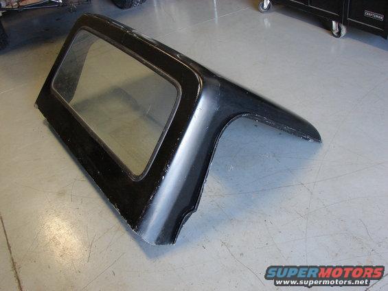 Black Jeep hardtop with windows, sitting on a garage floor