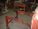 1964 Ford Fairlane - A section of a rusted vehicle frame is mounted on a red stand in a workshop setting.