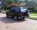 1996 Ford Bronco - A black Ford Bronco is parked on a residential street with a house and trees in the background.
