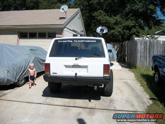 Rear view of white 1992 Jeep Cherokee with a sticker on the rear window