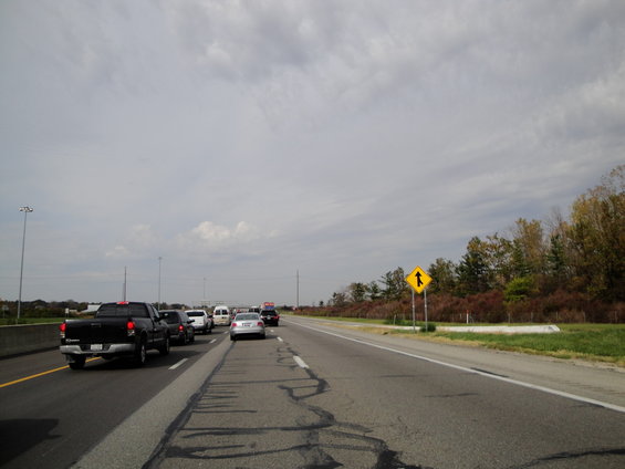Cars and trucks on a highway with a merge lane sign