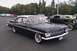1991 Ford Crown Victoria - A classic black 1959 Chevrolet Impala with distinctive tail fins is parked outdoors.