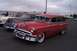 1991 Ford Crown Victoria - A vintage red station wagon with wood paneling is parked alongside other classic cars.