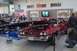 1991 Ford Crown Victoria - A red sedan with its hood open is displayed next to a black convertible at a car show.