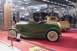 1991 Ford Crown Victoria - A green roadster with whitewall tires is displayed on a red carpet next to a wooden-bed truck.