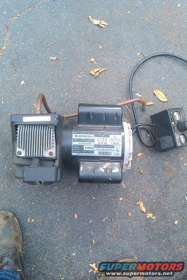 Electric motor with model number WL600802AJ and a separate control box, lying on asphalt