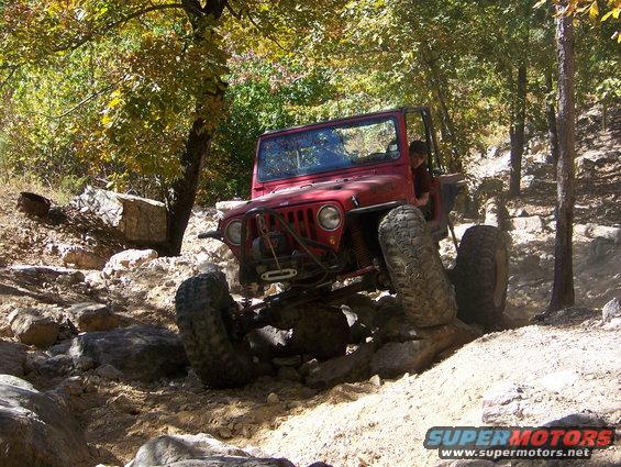 Red 1992 Jeep YJ navigating rocky terrain