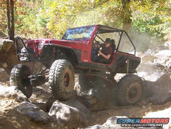 red 1992 Jeep YJ climbing over rocks on a trail