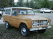 1966 Ford Bronco - A tan Ford Bronco with a white hardtop is parked on a grassy area next to a white SUV.