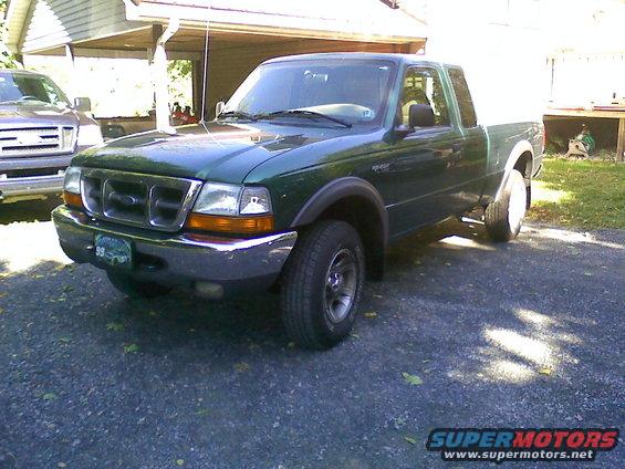 Green Ford Ranger pickup truck parked in a driveway, another truck is partially visible to the left