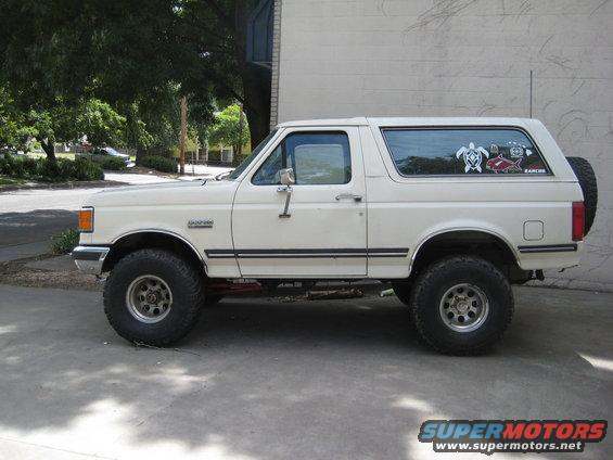 White 1990 Ford Bronco side view with off-road tires and decals on rear window