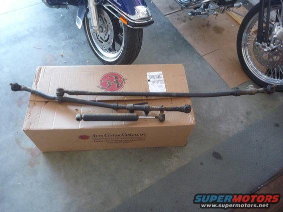 Steering linkage and shock absorber on a box. Motorcycle parts visible