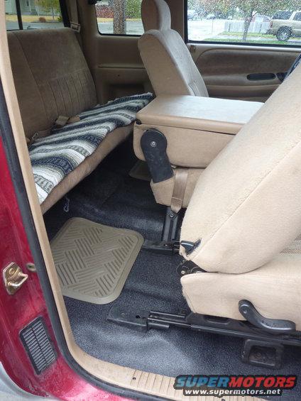 Interior view of a 1997 Dodge 2500 pickup truck, showing the rear bench seat with a blanket and the front center console