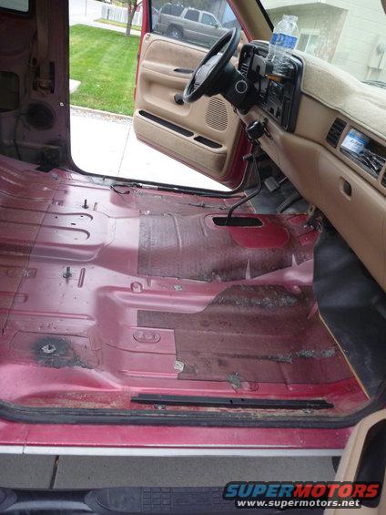 1997 Dodge 2500 interior with carpet removed, showing red floor and tan dashboard