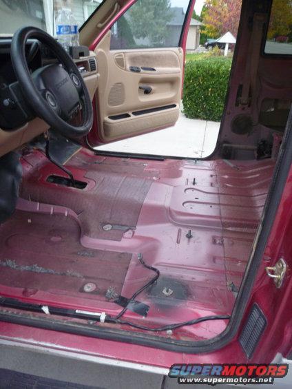 1997 Dodge 2500 interior with removed seats, red floor, tan door panels, and steering wheel