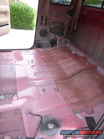 Interior of a red 1997 Dodge 2500 pickup truck with carpet removed
