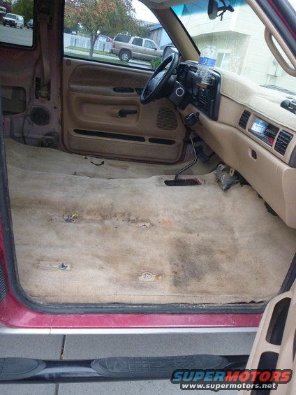 Interior of a 1997 Dodge 2500 pickup truck, showing the driver's side door, dashboard, and worn carpet