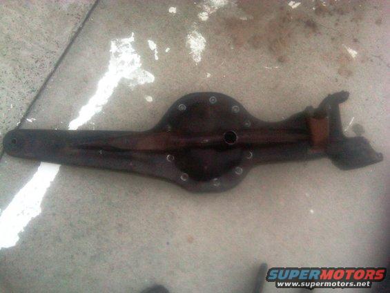 Dark rear axle differential housing on concrete. Water stains and white paint splatters are visible