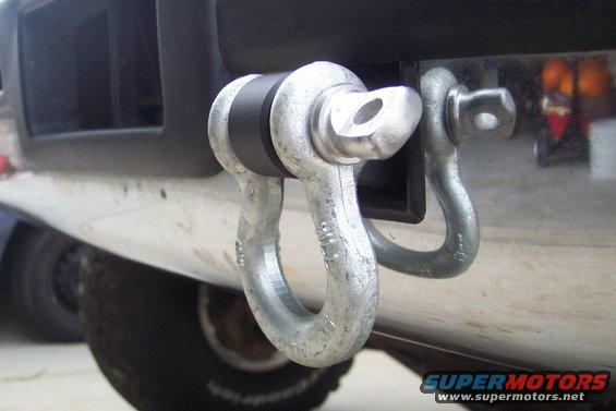 Close-up of two metal tow hitch shackle mounts attached to a vehicle's bumper
