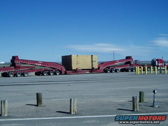 Red tractor-trailer with lowboy trailer carrying a large box