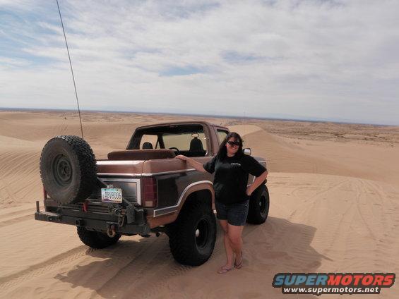 Brown Ford Bronco with spare tire on rear, parked on sand dune