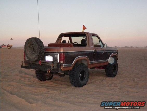Brown and black Ford Bronco with spare tire on rear, seen from the rear 3/4 angle